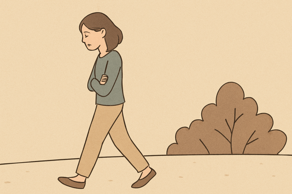 うつむきながら腕を組んで歩く女性と、その横にある丸い木のシルエット