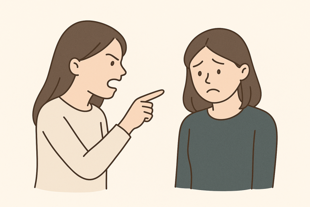 怒った表情の女性が、指を突き出してもう一人の女性を非難している様子。非難されている側の女性は、うつむき気味で不安げな表情をしている。